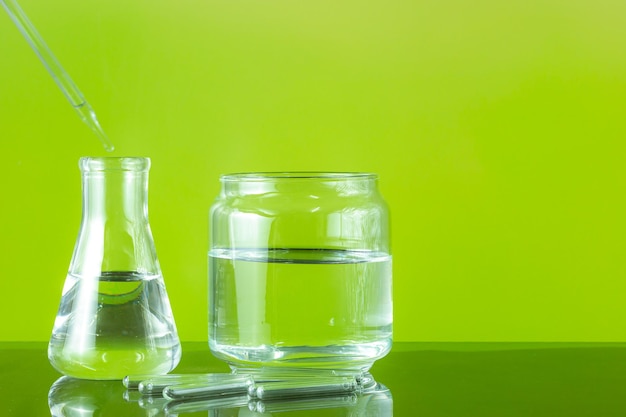 Set of chemical glassware for science experiment on gradient green background