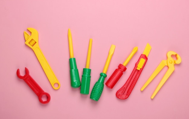 Set of children's toy work tools on pink pastel