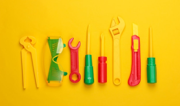 Set of children's toy work tools on yellow.