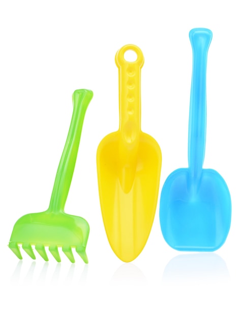 A set of children's toys for playing in the sandbox Colored rake and shovel made of plastic isolated on a white background closeup Early child development children's leisure concept