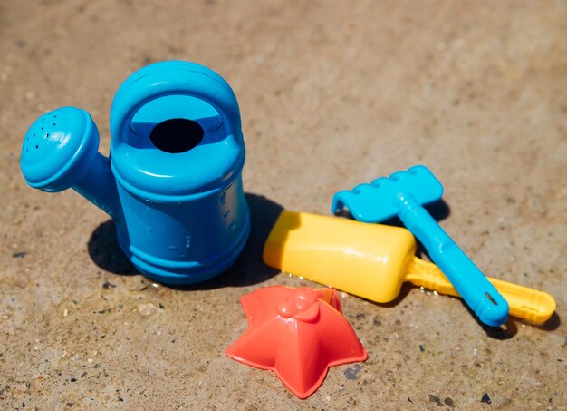 A set of children's toys for playing in the sandbox Colored rake shovel watering can made of plastic closeup Early development of the child the concept of children's leisure