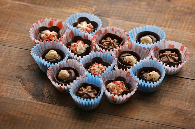 Set of chocolate candies forming heart on a wooden background