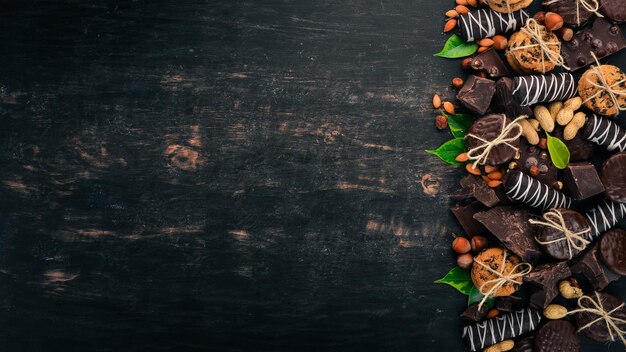 Set of chocolate with nuts cookies and cocoa On a black wooden background Top view Copy space for text