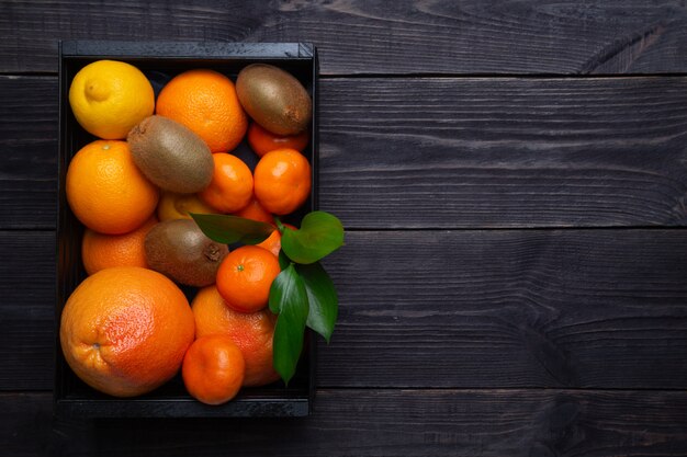 暗い背景のブラックボックスで免疫力を高めるための柑橘系の果物のセット。免疫力を高めるというコンセプト。