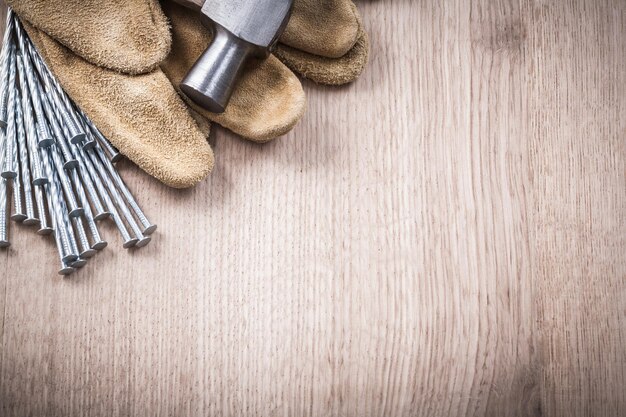 Set of claw hammer leather safety gloves and stainless nails on wooden background construction concept