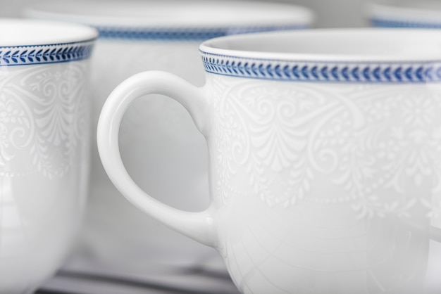 Set of clean white cups located on the shelf