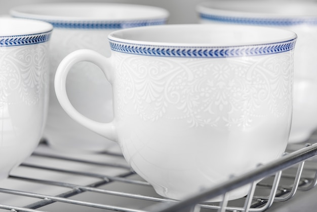 Set of clean white cups located on the shelf