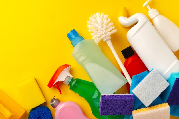 set of cleaning supplies on yellow color background
