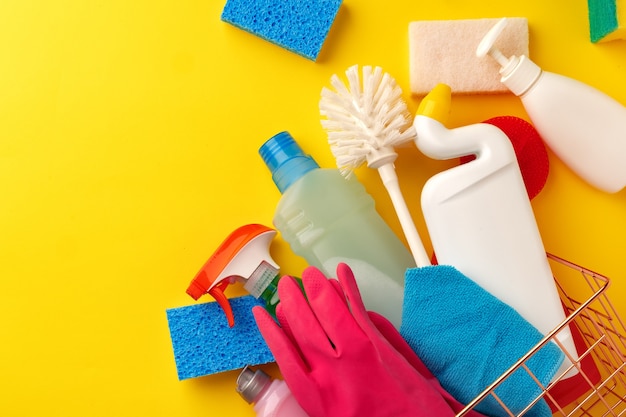 Set of cleaning supplies on yellow color background