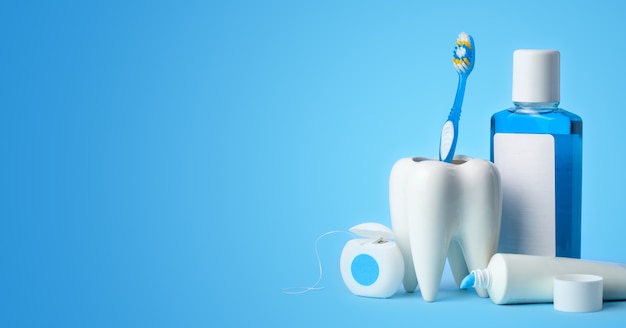 Photo set for cleaning teeth and mouth. toothpaste, toothbrush, dental floss and mouthwash on a blue background.