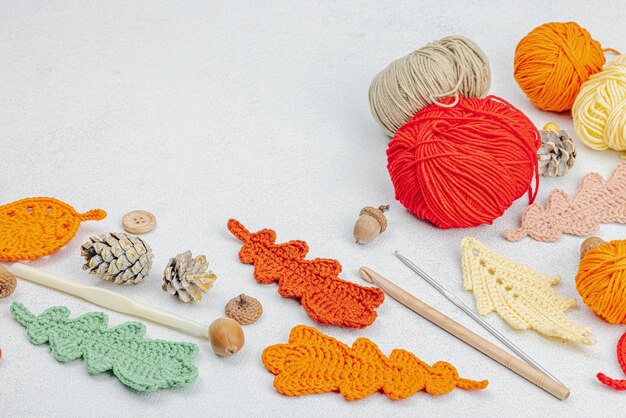 Set of clew of thread for knitting Crocheted different leaves handmade autumn hobby concept Props and special craft tools on light stone concrete background copy space