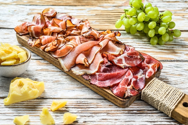 Set of cold cured italian meat Ham, prosciutto, pancetta, bacon. White wooden background. Top view.