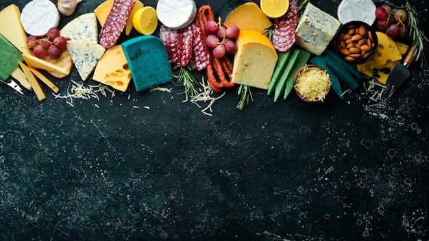 Set of colored cheese sausages salami and snacks On a dark background Free copy space Top view