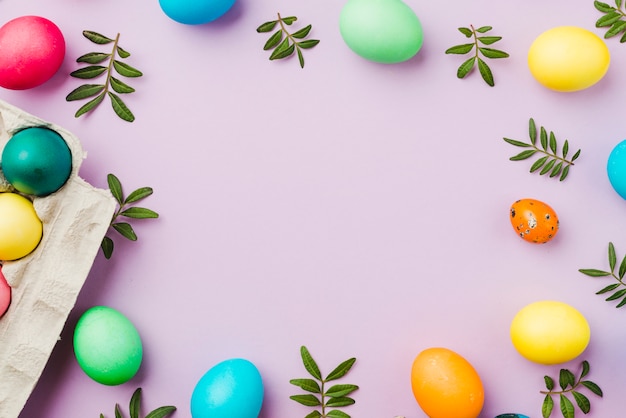 Photo set of colored eggs and leaves near container