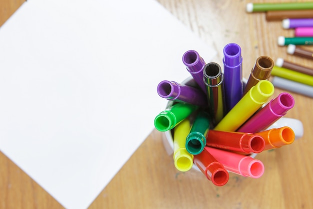 A set of colored markers and a sheet of white paper on the table.