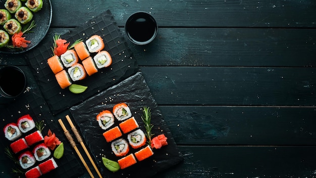 Set of colored sushi in black plates Japanese food Top view Free space for your text