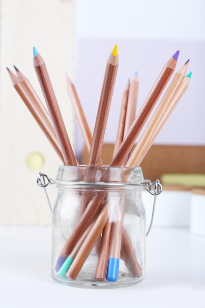 Set of coloured pencils in a glass pot on a table