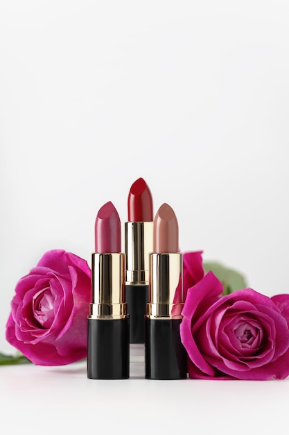 Set colourful lipstick with pink roses on white background.