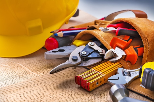 Set of construction tools in toolbelt close up on wooden board