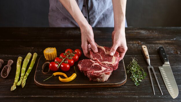 Set for cooking a festive dinner for two. two raw marbled beef steaks, spices, vegetables 