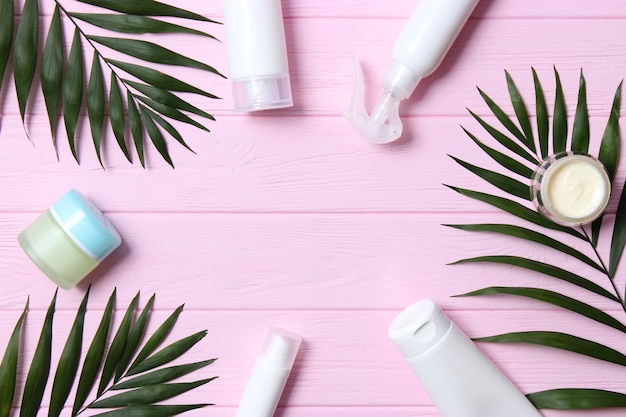 Set of cosmetic jars of white color and palm branches on a colored background