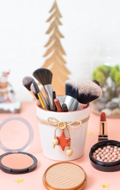 A set of cosmetics on a pink background with a christmas decoration