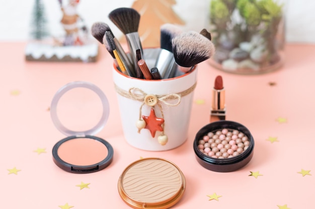 A set of cosmetics on a pink background with a christmas decoration