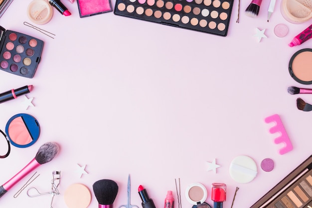 Set of cosmetics products forming frame on pink background