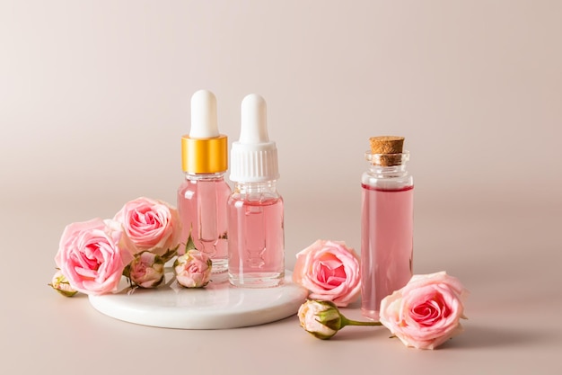 パステル背景にバラの花びらの抽出物をベースにしたさまざまなボトルに入った化粧品セット顔のスキンケア自然化粧品