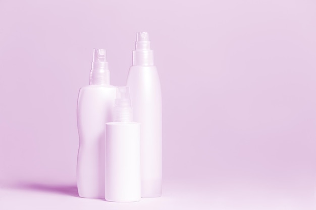 Set cosmetische producten in roze en grijze containers op lichte achtergrond.