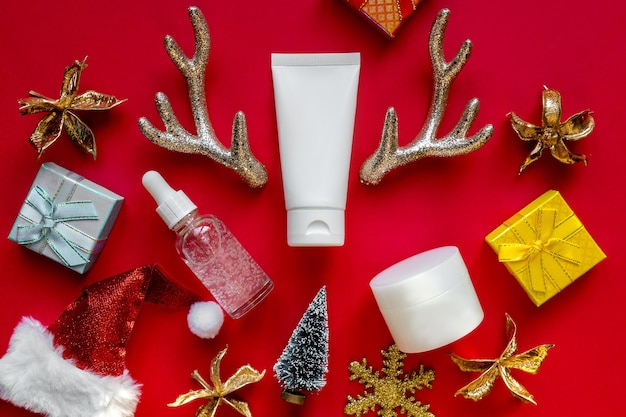 Set cosmetische producten op feestelijke rode achtergrond met nieuwjaarsversieringen, plat met ruimte voor tekst. winterverzorging. ideeën voor cadeaus voor vrouwen.