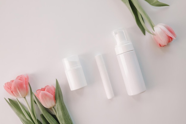 Set cosmetische verzorgingsproducten op een witte achtergrond en tulpen