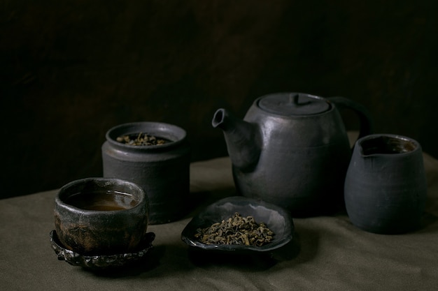 Set of craft handmade ceramic teapot and cups with dark background