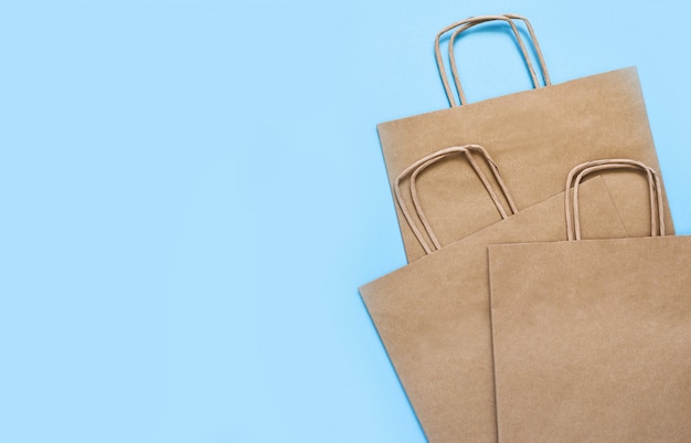 Set of craft paper bags for shopping on a blue table.