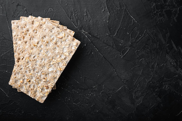 Set of crispy breads set, on black dark stone table background, top view flat lay, with copy space for text