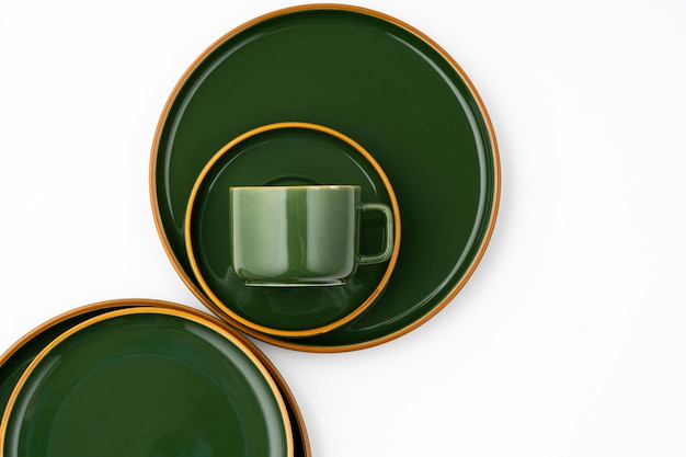 A set of dark green ceramic tableware with orange outlines on a white background