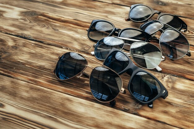 Set of dark sunglasses on brown wooden surface