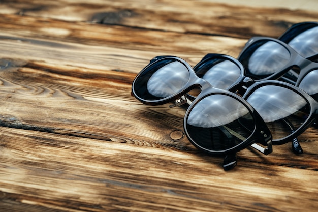 Set of dark sunglasses on brown wooden surface