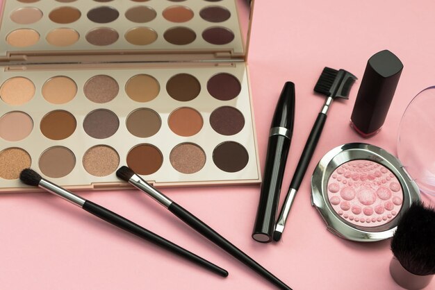 Set of decorative cosmetics eyeshadow palette brushes mascara on a pink background