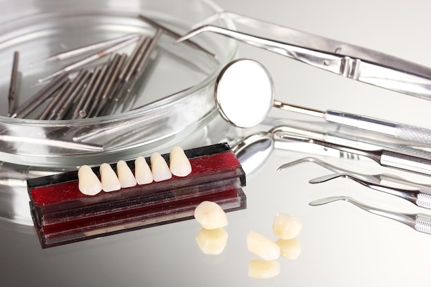 Set of dental tools with denture on grey background