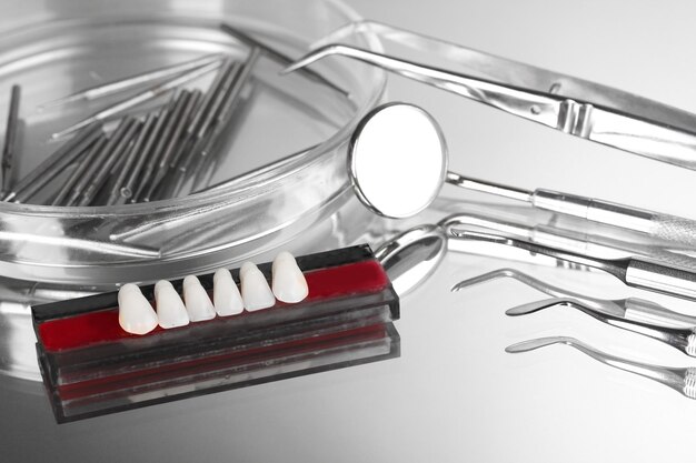 Set of dental tools with denture on grey background