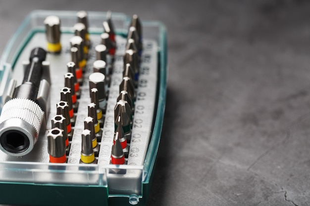 A set of different bits for screwdrivers and repairs in a box on a gray background