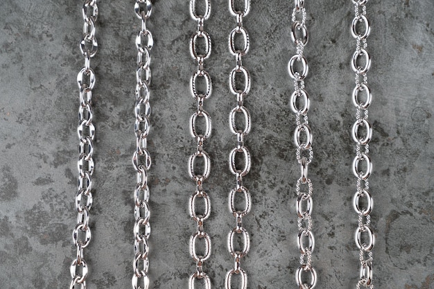 Set of different chains on a concrete background Chain connection types of metal chains