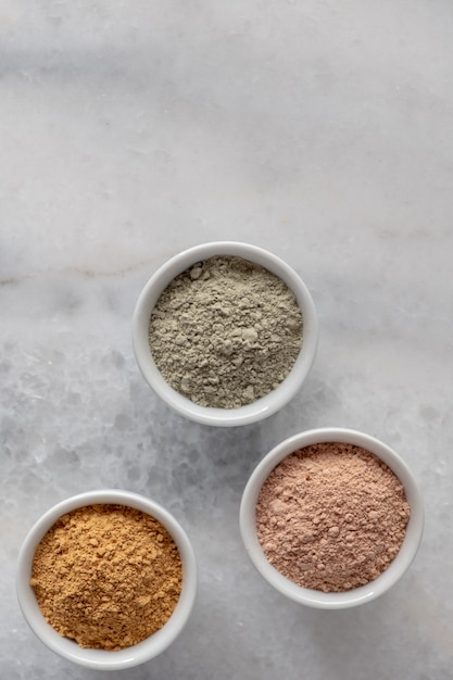 Set of different cosmetic clay mud powders on white surface