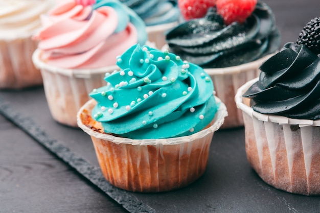 Set of different delicious cupcakes on dark