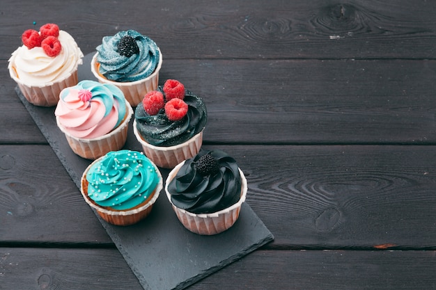 Set of different delicious cupcakes on dark