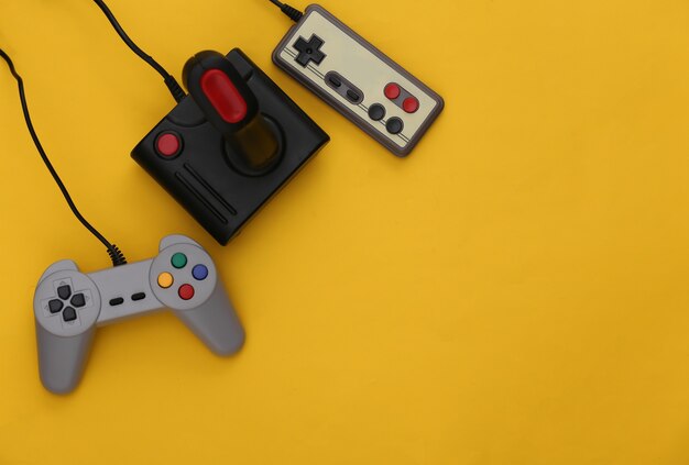 Set of different retro gamepads and joysticks on a yellow background. Video game. Flat lay, top view, copy space