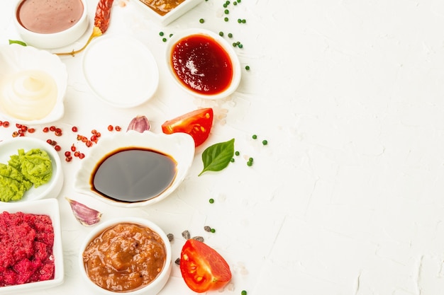 Set of different sauces - ketchup, mayonnaise, barbecue, soy, chutney, wasabi, adjika, horseradish, aioli , marinara. Trendy hard light, dark shadow. White putty background, top view