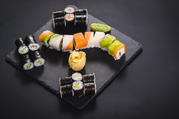 A set of different sushi rolls with caviar on black background