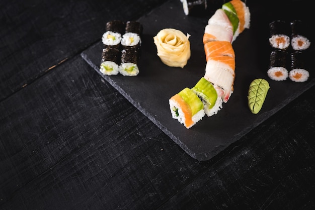 A set of different sushi rolls with caviar on black background